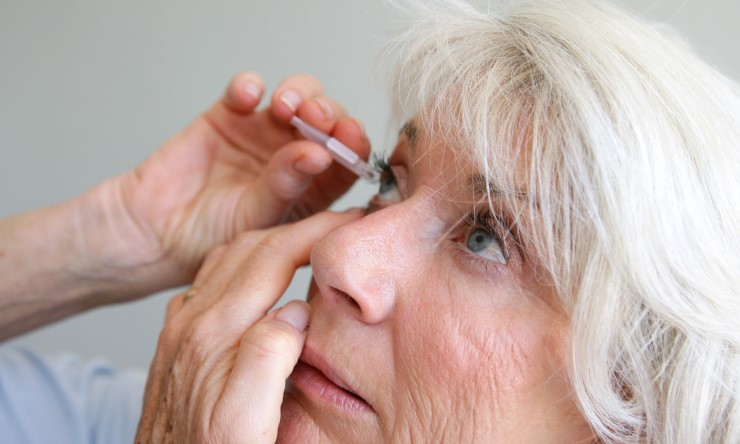 Older woman taking eye drops