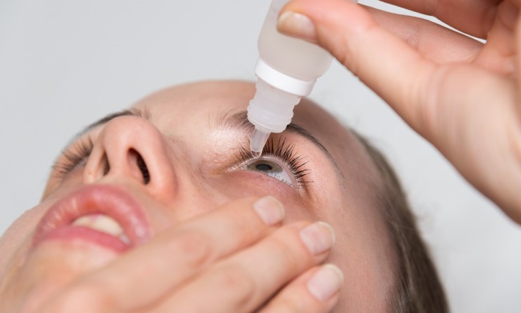 Woman putting drops in her eye