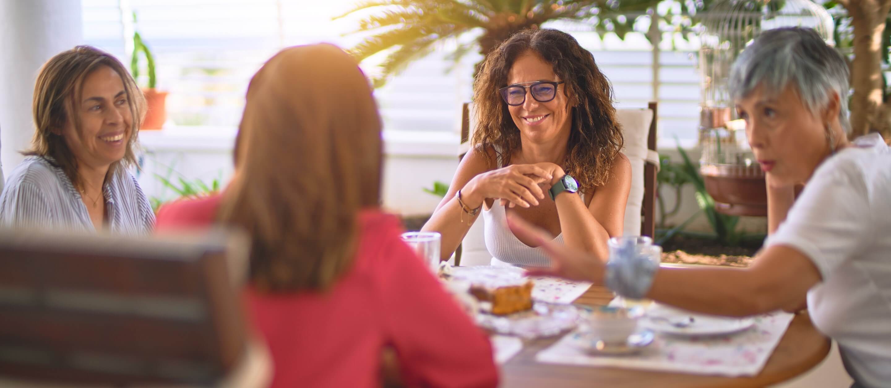 Group of happy women sitting together talking and drinking coffee on an outdoor terrace