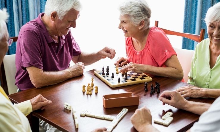 Group of retirees happily enjoying board games and conversation