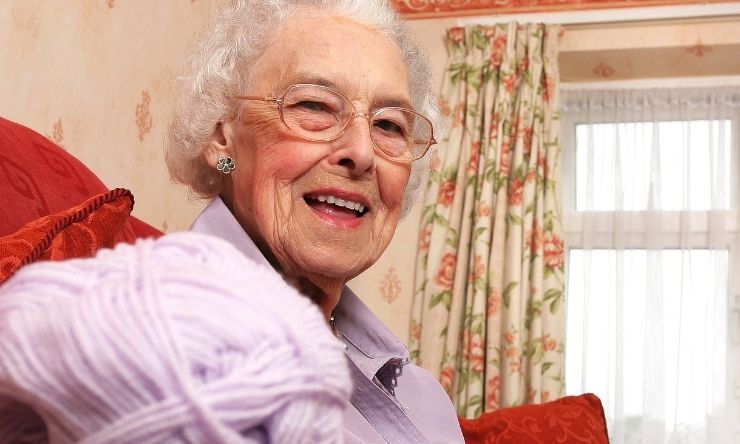 Older lady sitting in lounge room with knitting yarn