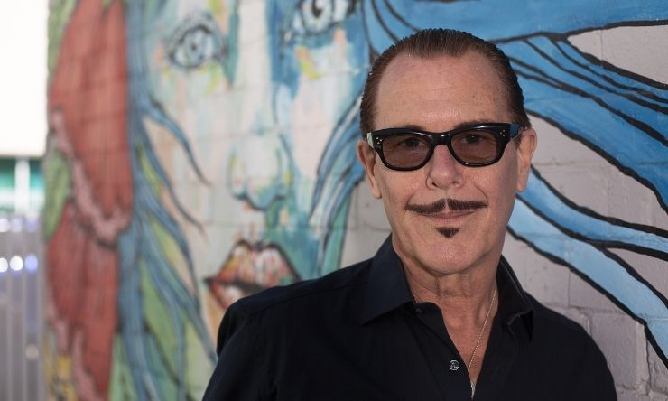 Kirk Pengilly leaning against wall with grafitti