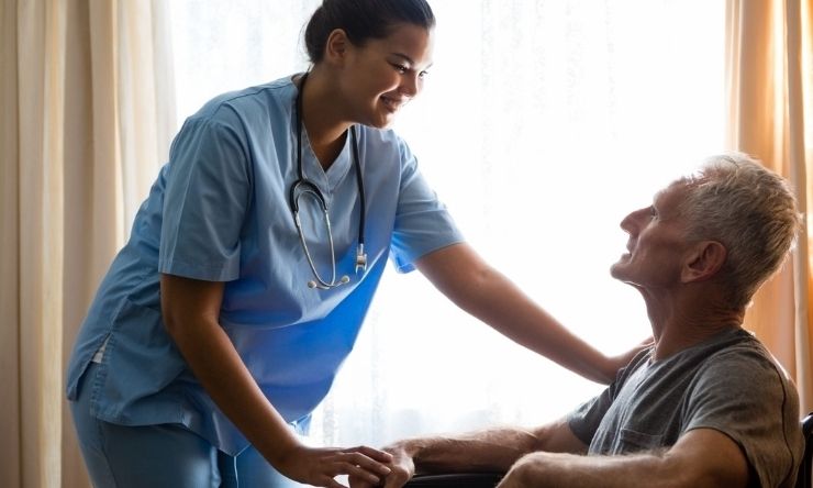 Nurse comforts man in wheelchair