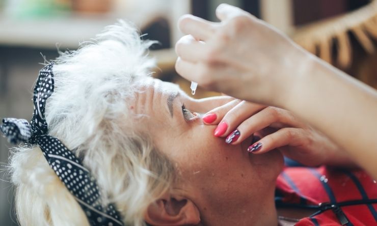 Woman leaning back and administering eye drops