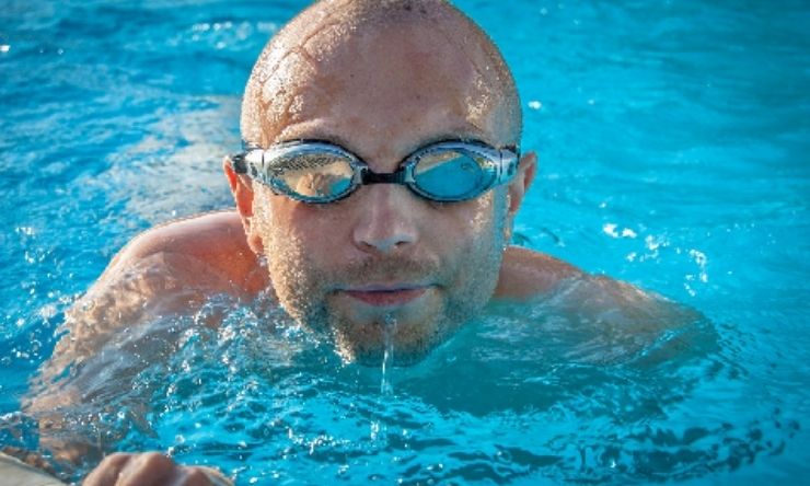 Man swimming in pool wearing goggles