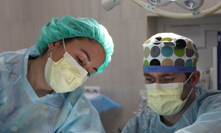 Two surgeons wearing masks and scrubs in operating theatre