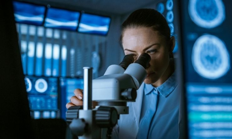 Research Technician using microscope in laboratory