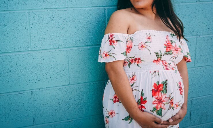 Young Hispanic woman holding her pregnant stomach