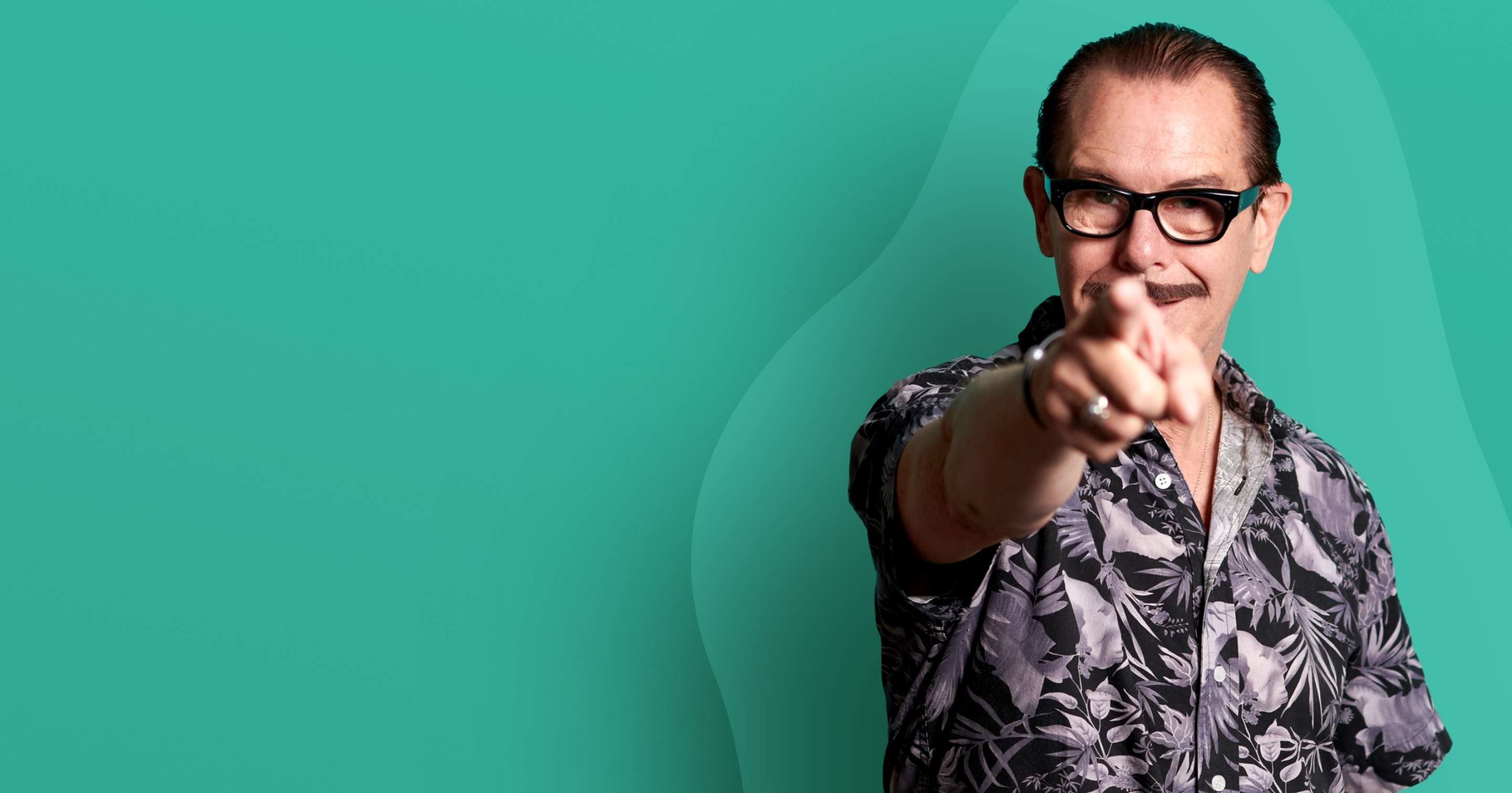 Image of man with dark hair, black thick rimmed spectacles, pointing straight at the camera