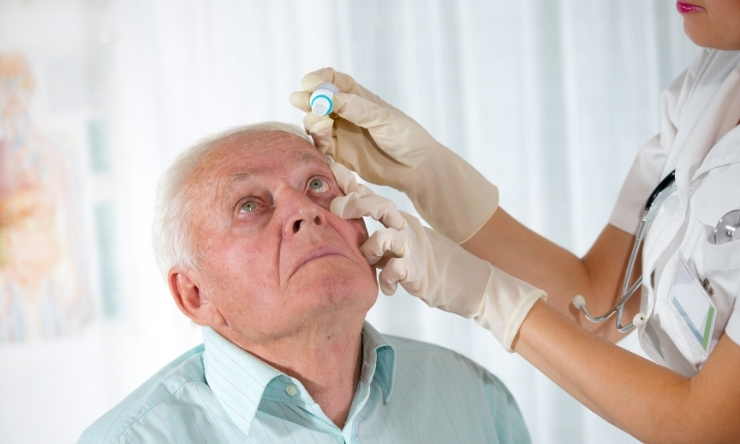 Image of elderly man having eye drops administered by nurse