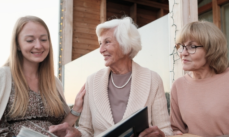 Image of a grandmother, mother, and daughter looking through family albums.