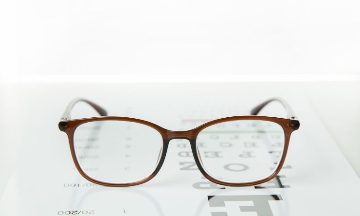 Image of brown reading glasses resting on an alphanumeric vision test card