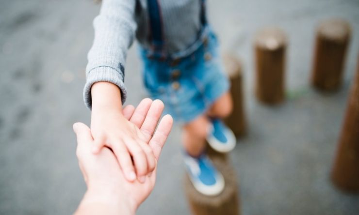 Image of child's hand resting on an adult's reached out hand