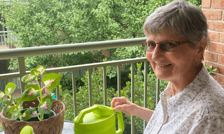 Elaine watering a plant on her balcony