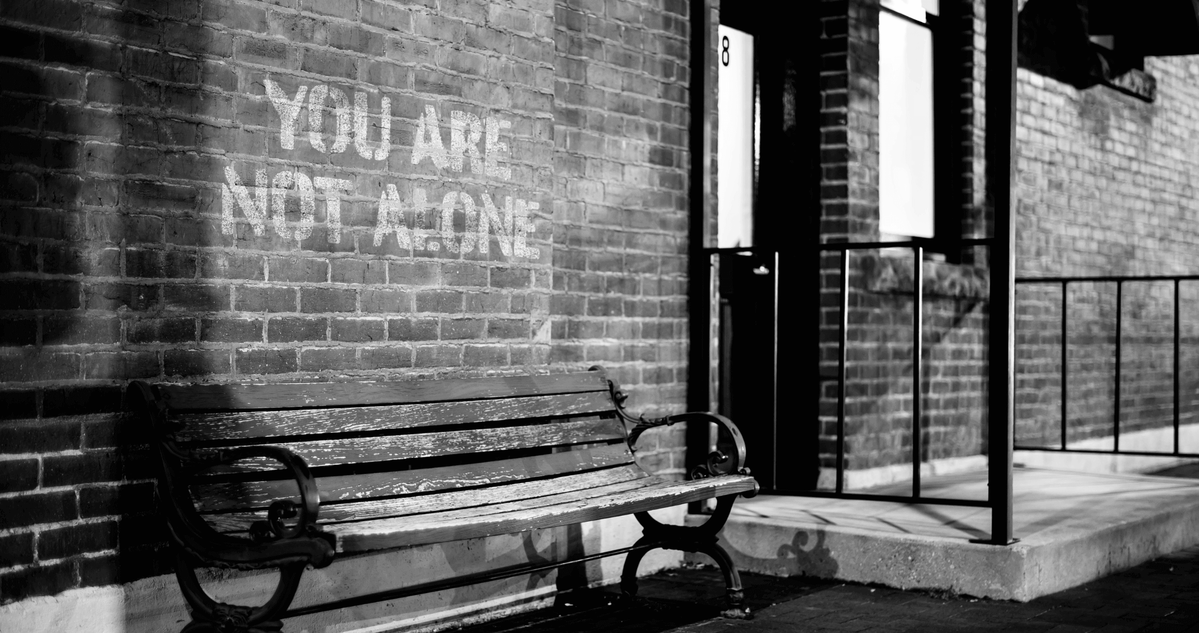 The words 'You Are Not Alone' painted in large capital letters on a brick wall