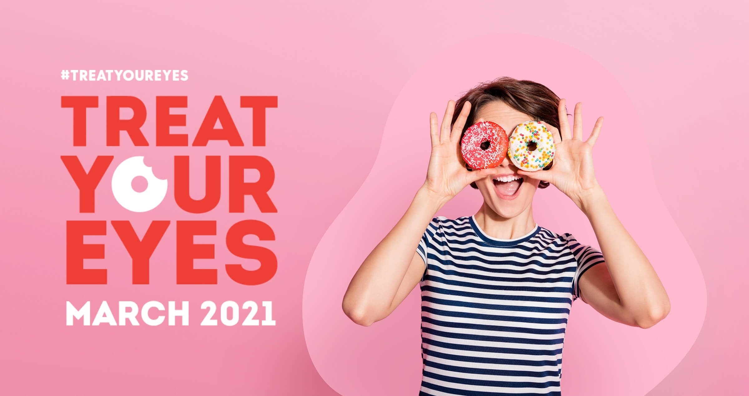 Image of woman holding up iced donuts over her eyes and smiling