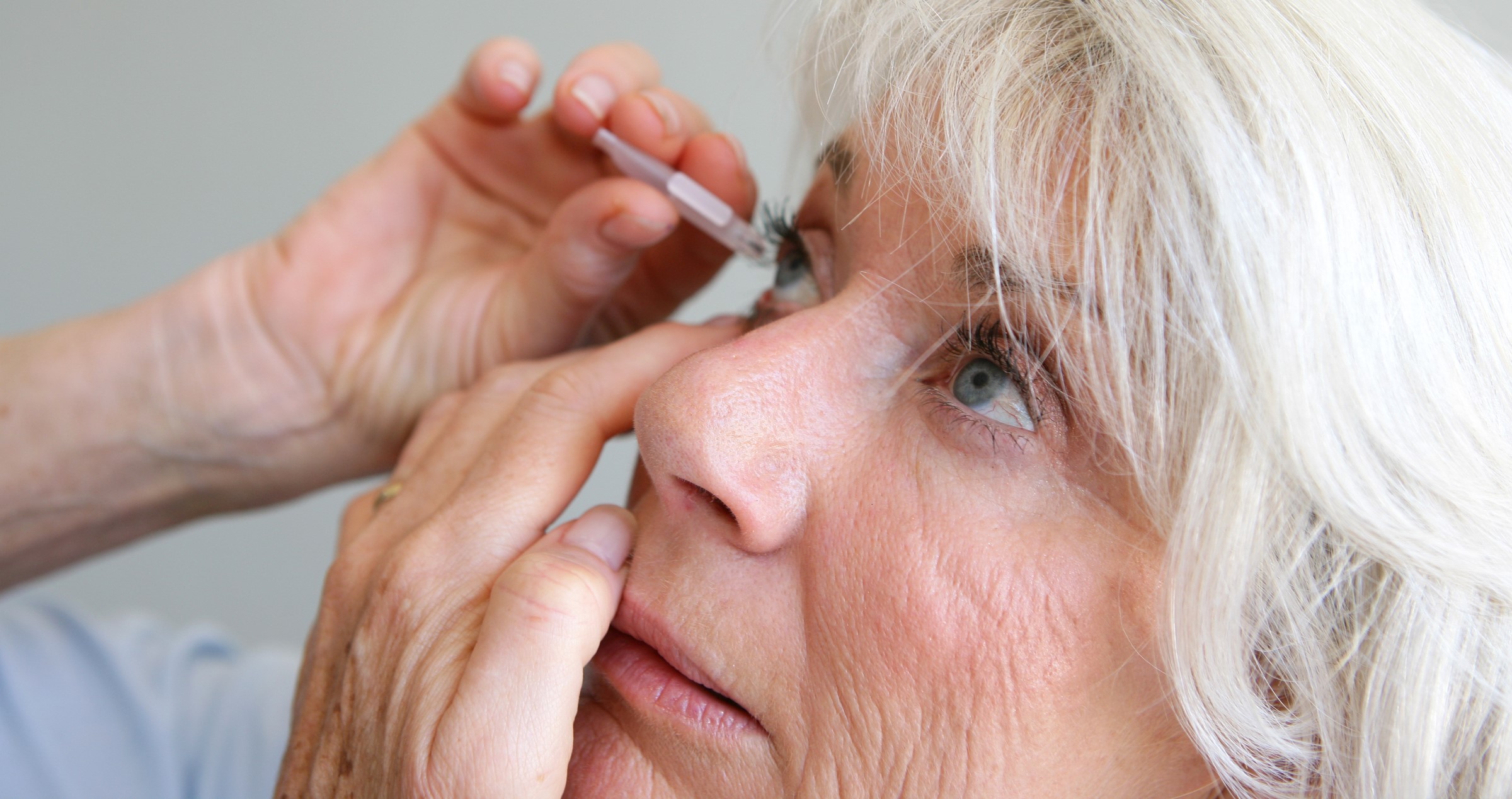 Older woman taking eye drops