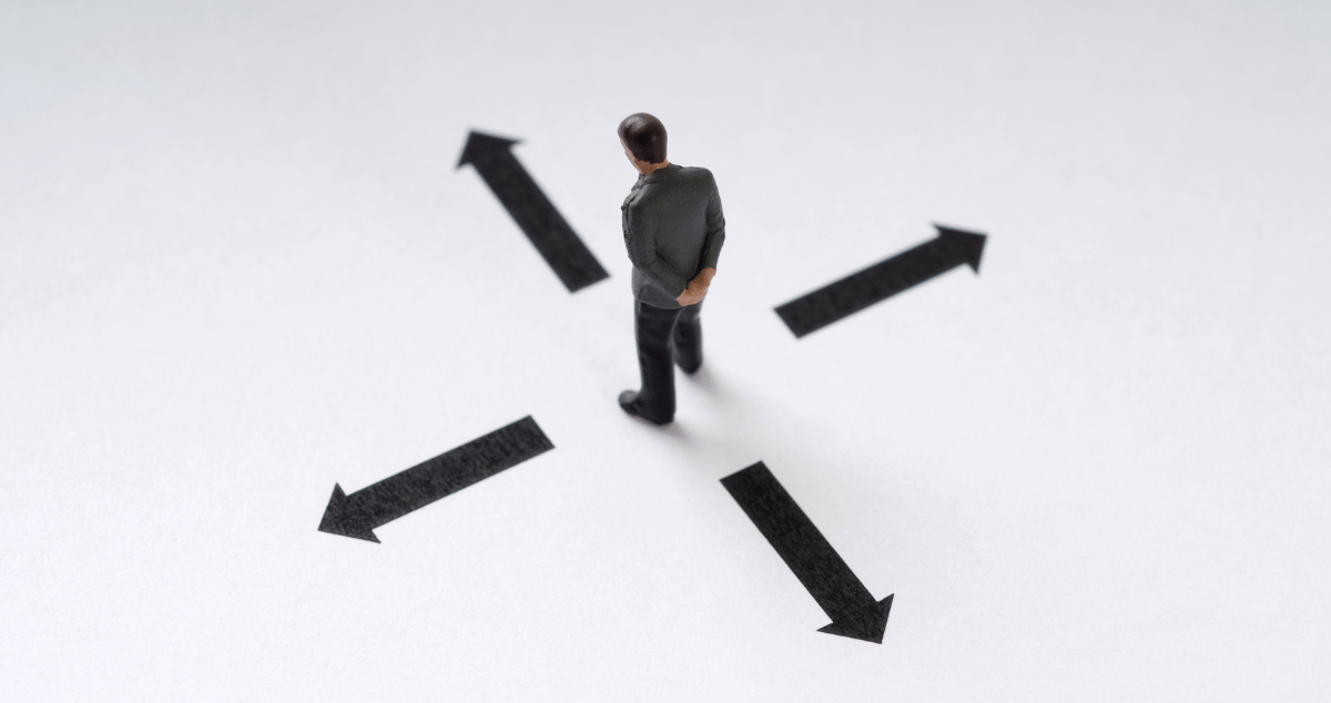 Man looking at arrows pointed in different directions to make a decision