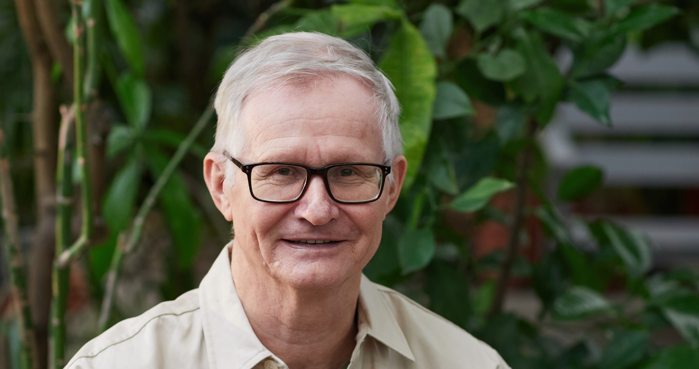 Image of 75 year old man in glasses with greenery in background