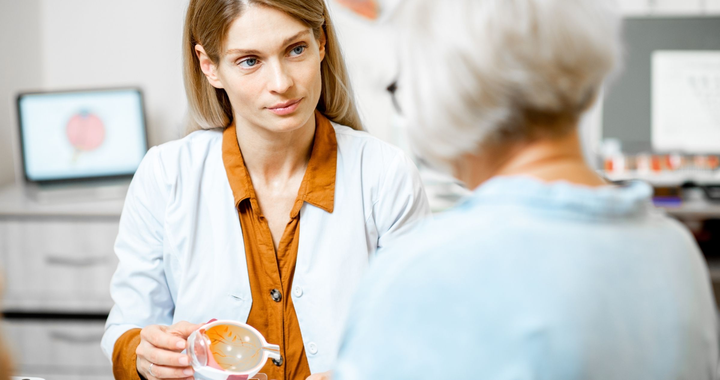 Doctor showing woman eye anatomy model