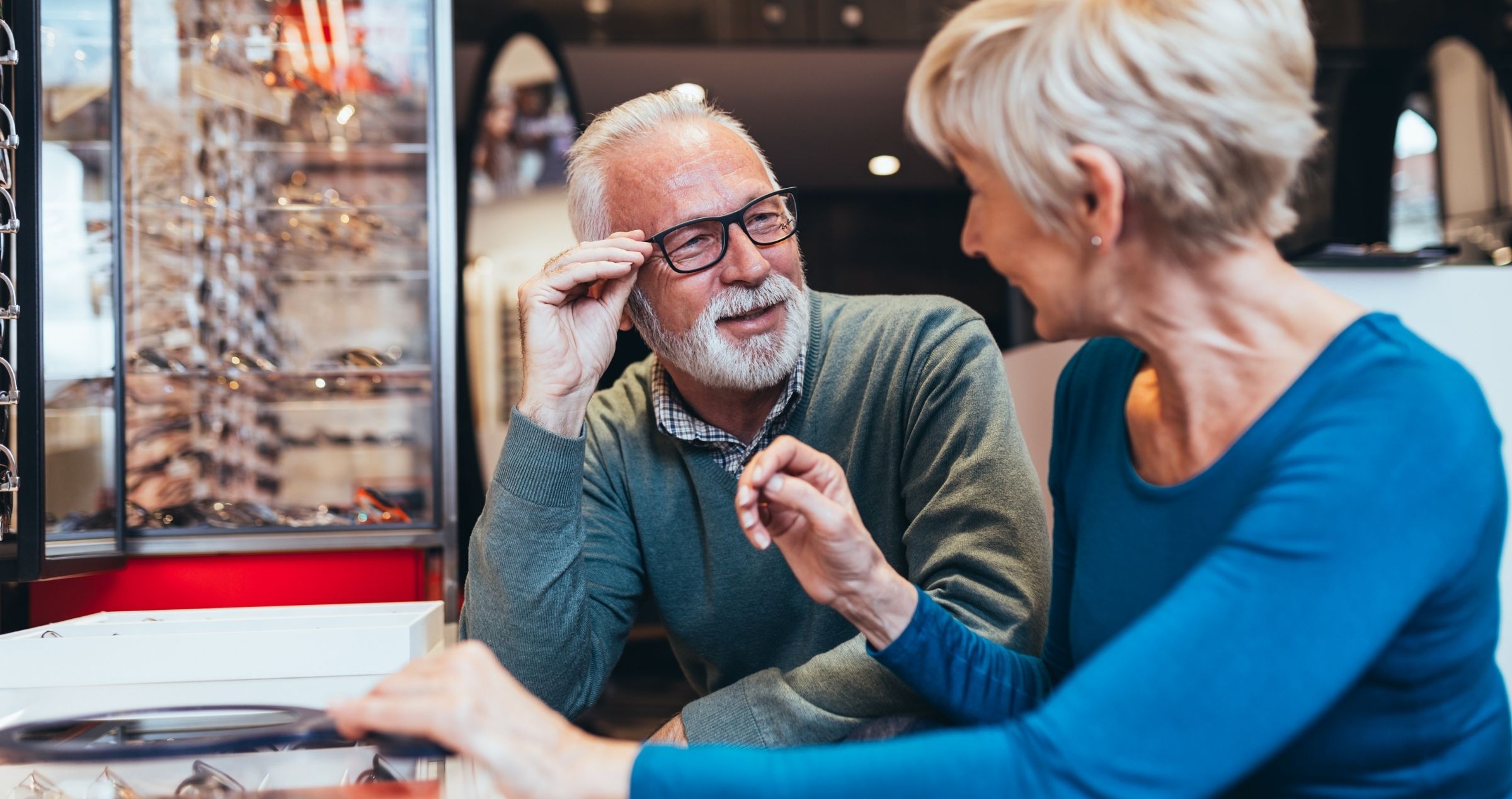 Image of older man and woman trying on glasses at an optometrist