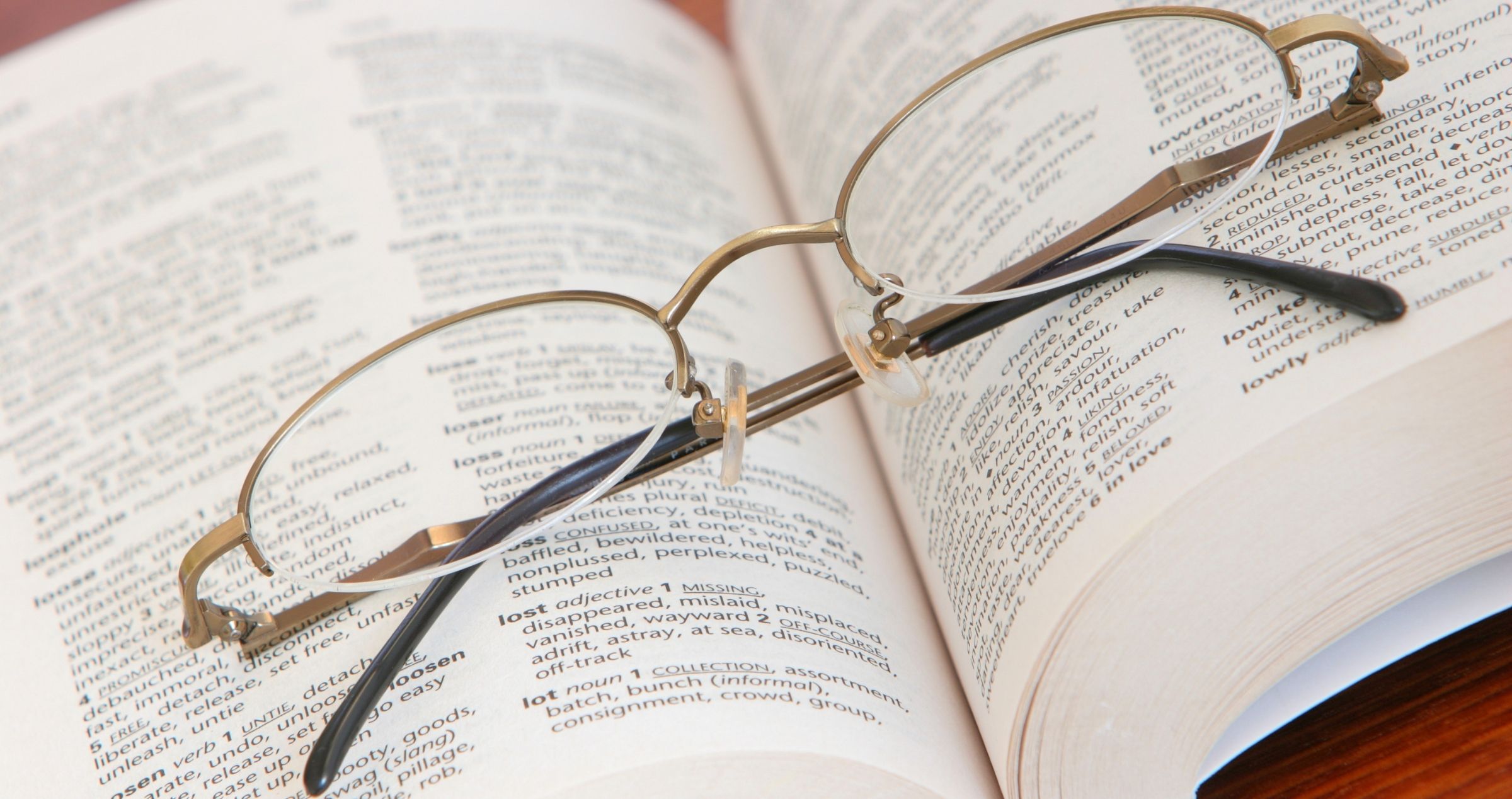 Image of folded reading glasses sitting on an open book