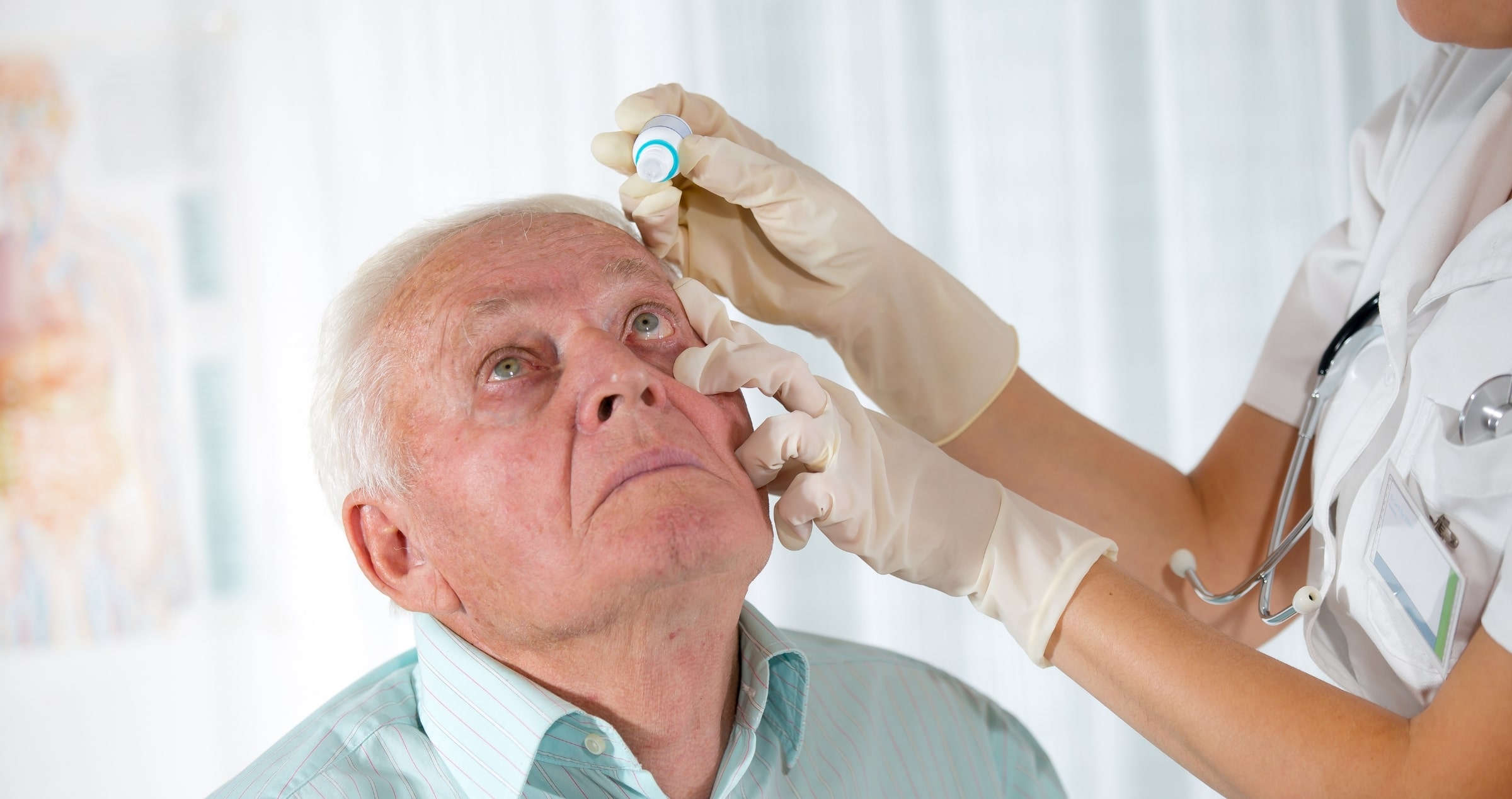 Image of elderly man having eye drops administered by nurse