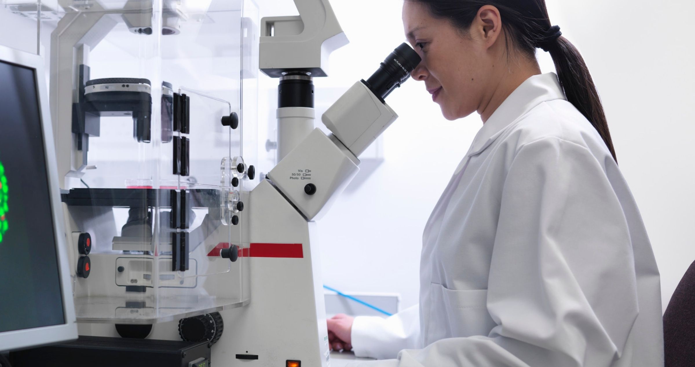Image of scientist looking in microscope in lab