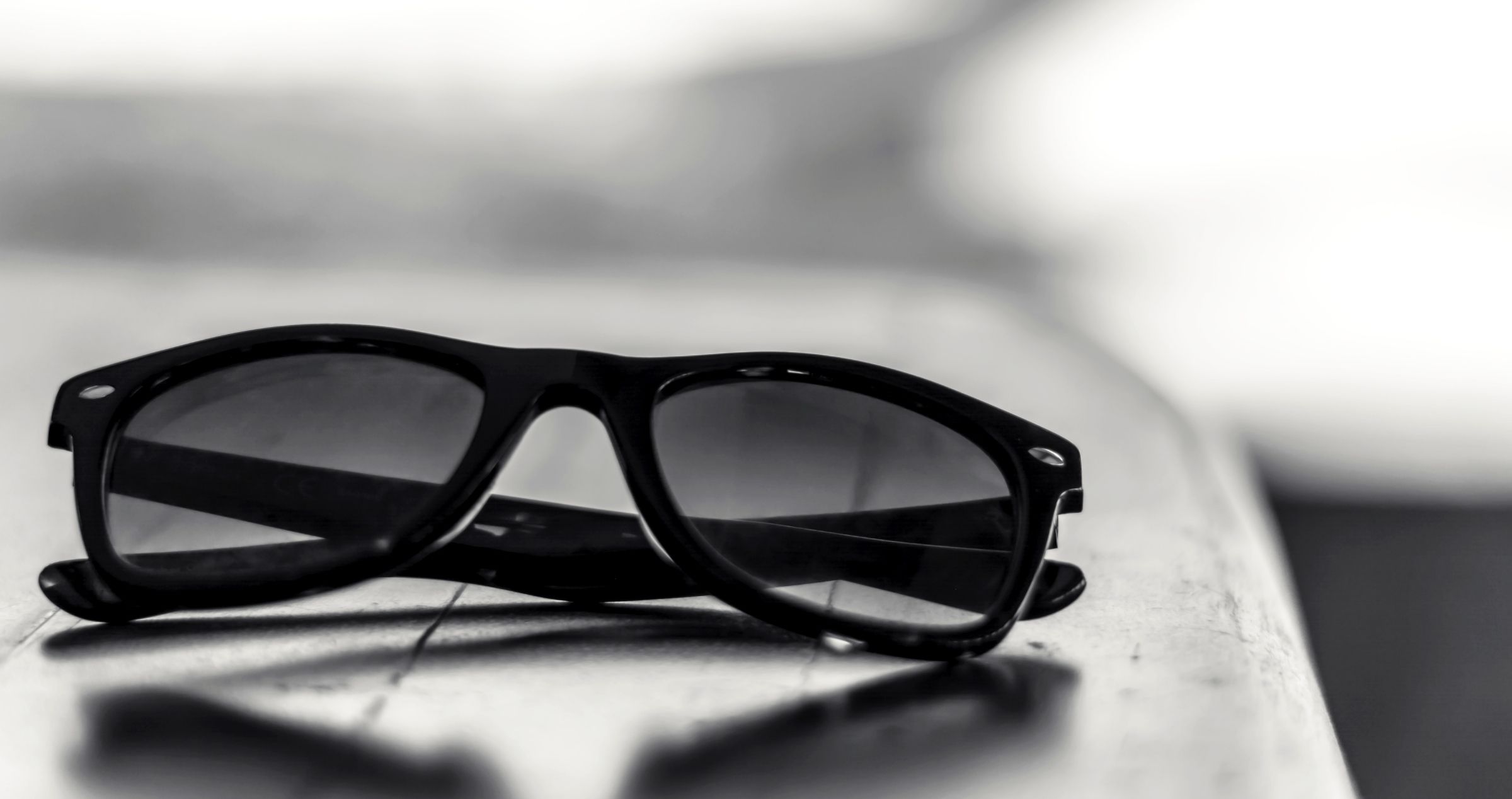 Image of dark folded sunglasses on edge of table