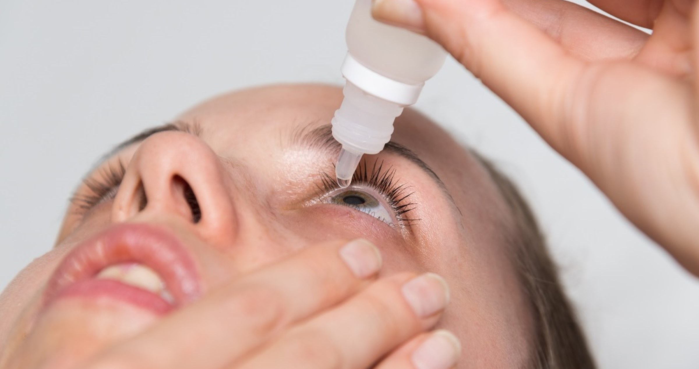 Woman putting eye drops in her eye.