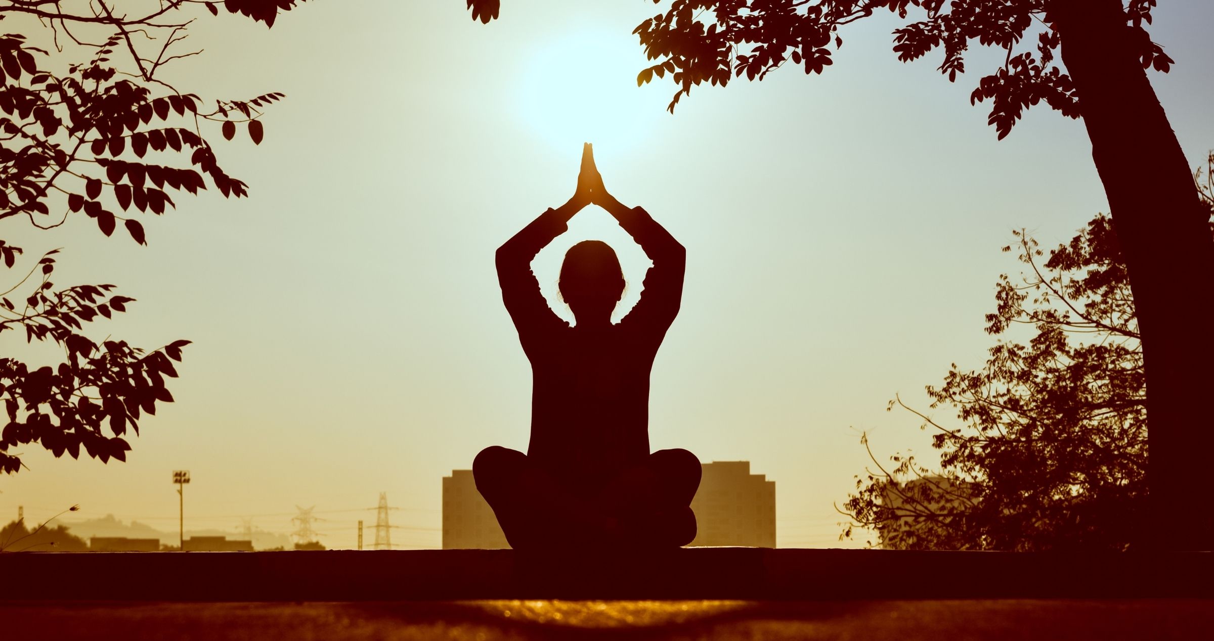 Silhouette of person in salute the sun yoga pose at sunrise