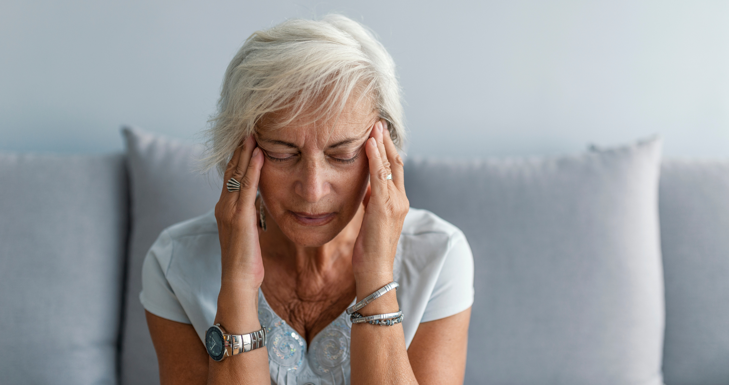 Image of woman suffering from a migraine with her hands on her temples 