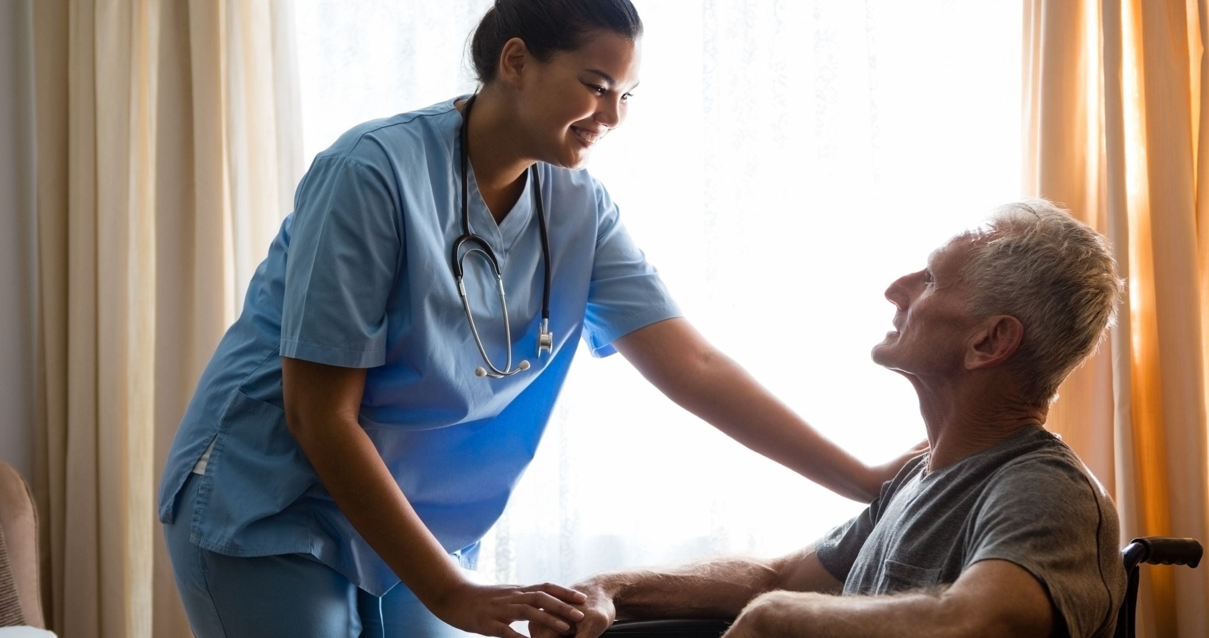 Nurse comforts man in wheelchair