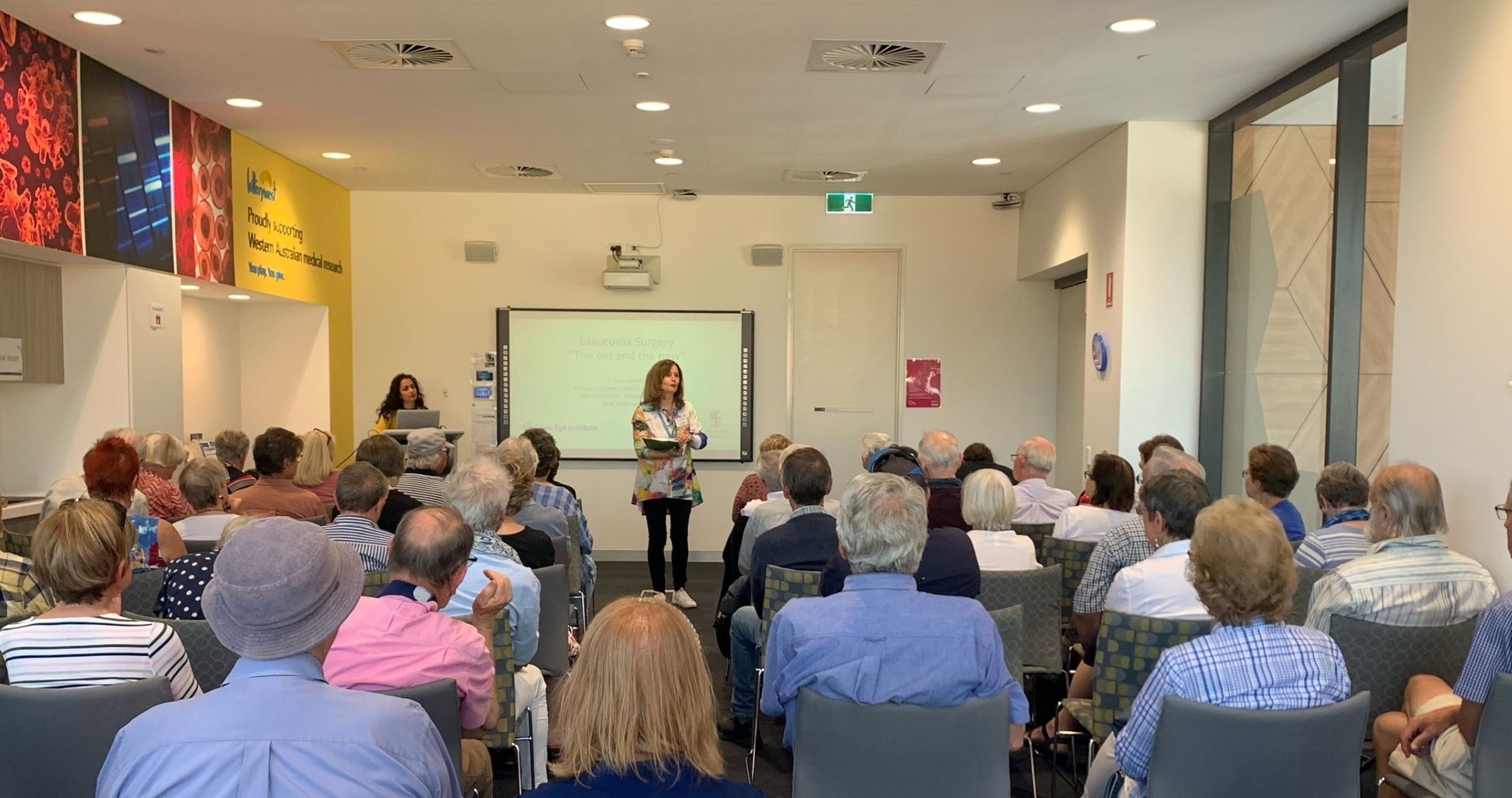 Image of audience in conference room and a female speaker 