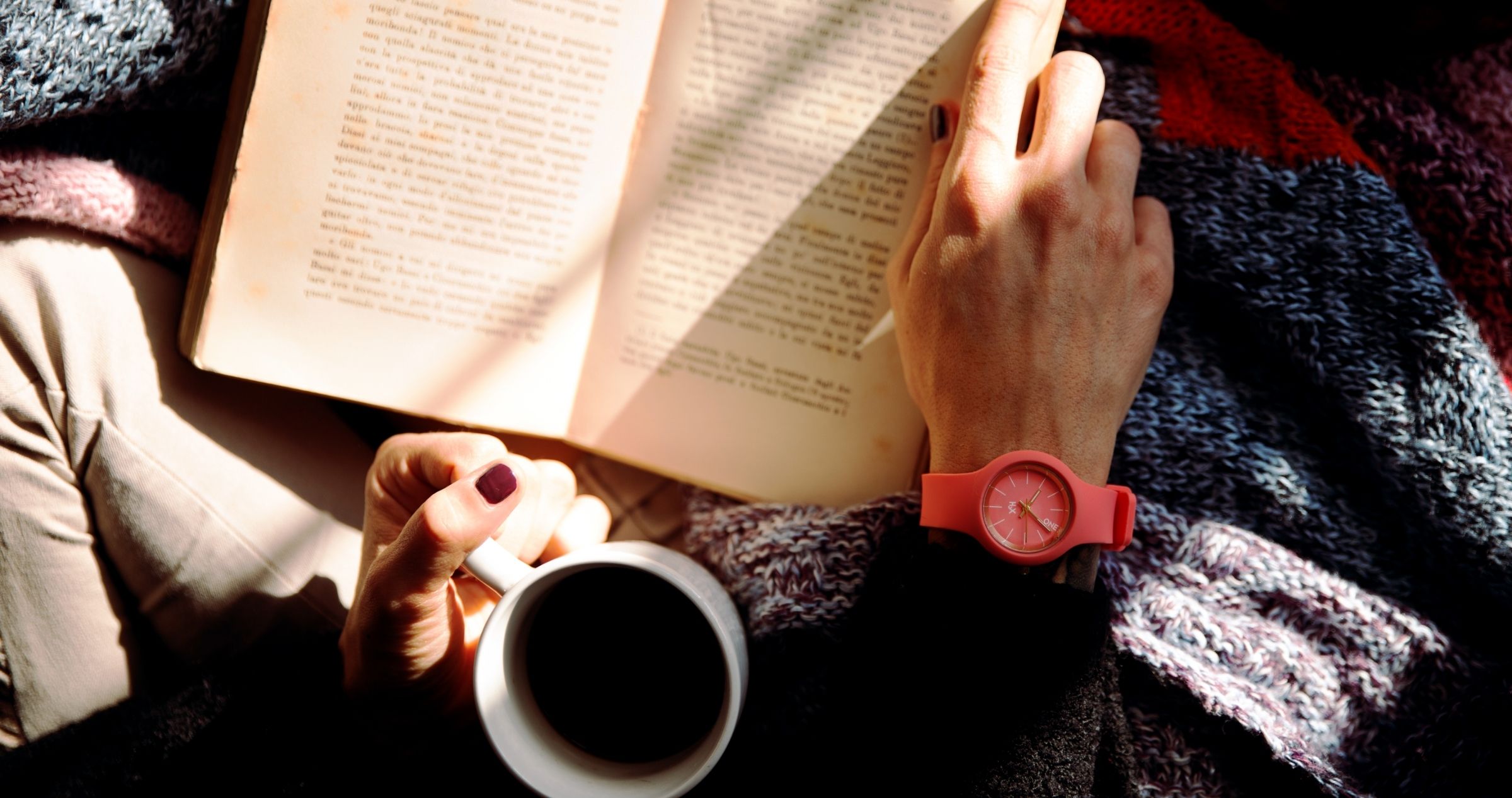 Female hands holding a book and a cup of coffee