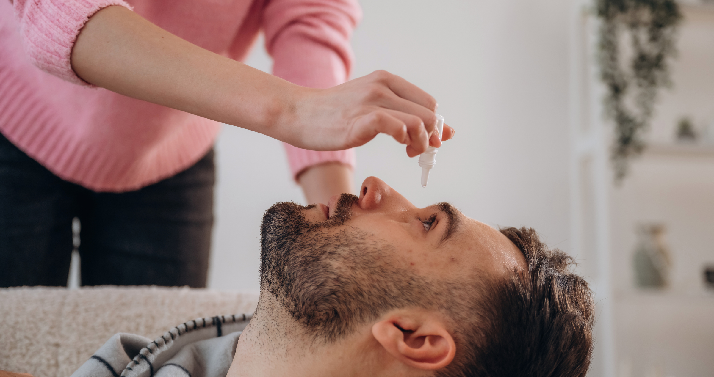 Lady putting drops into ,mans eyes