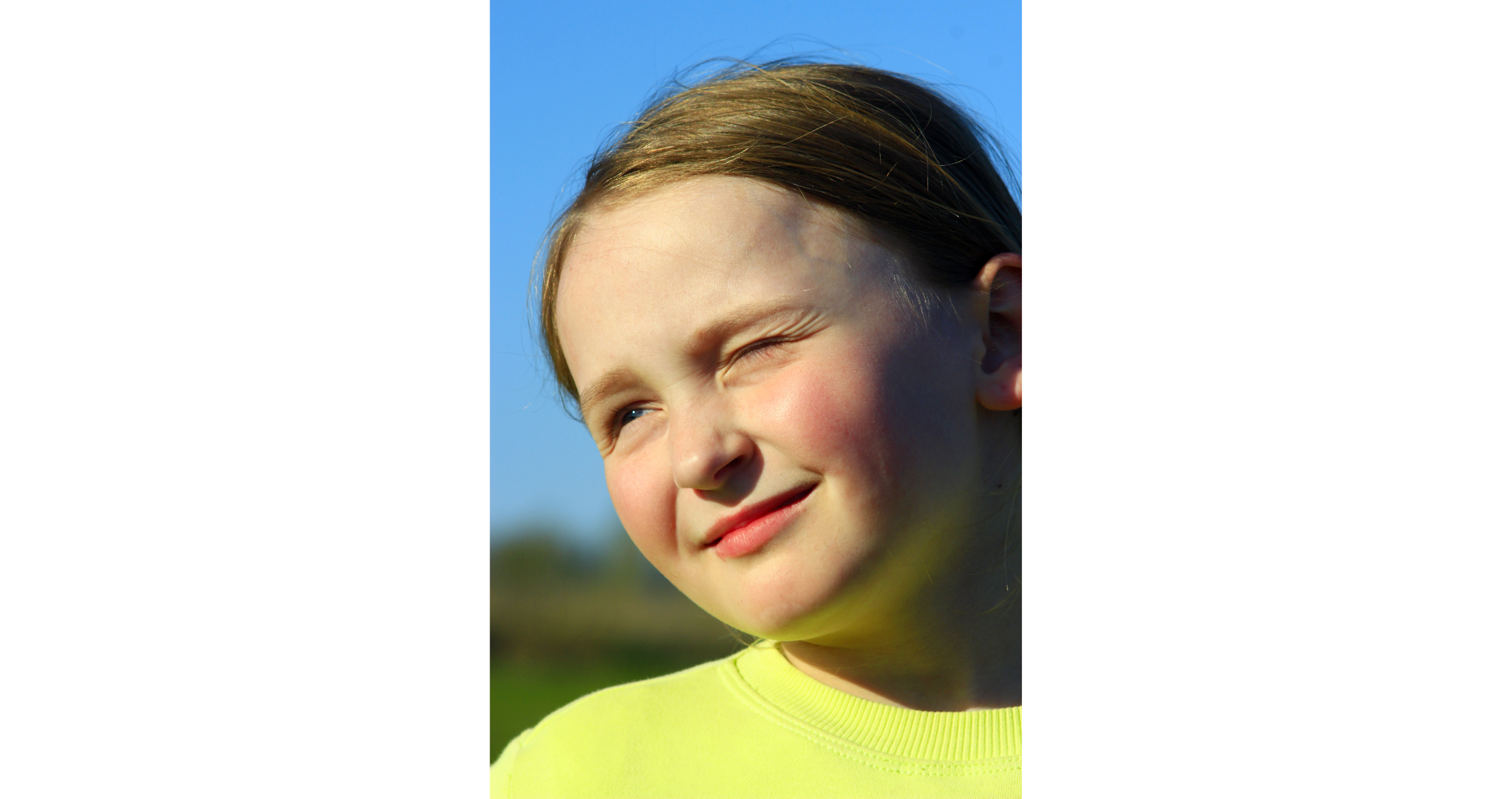 A young girl squinting into the sun