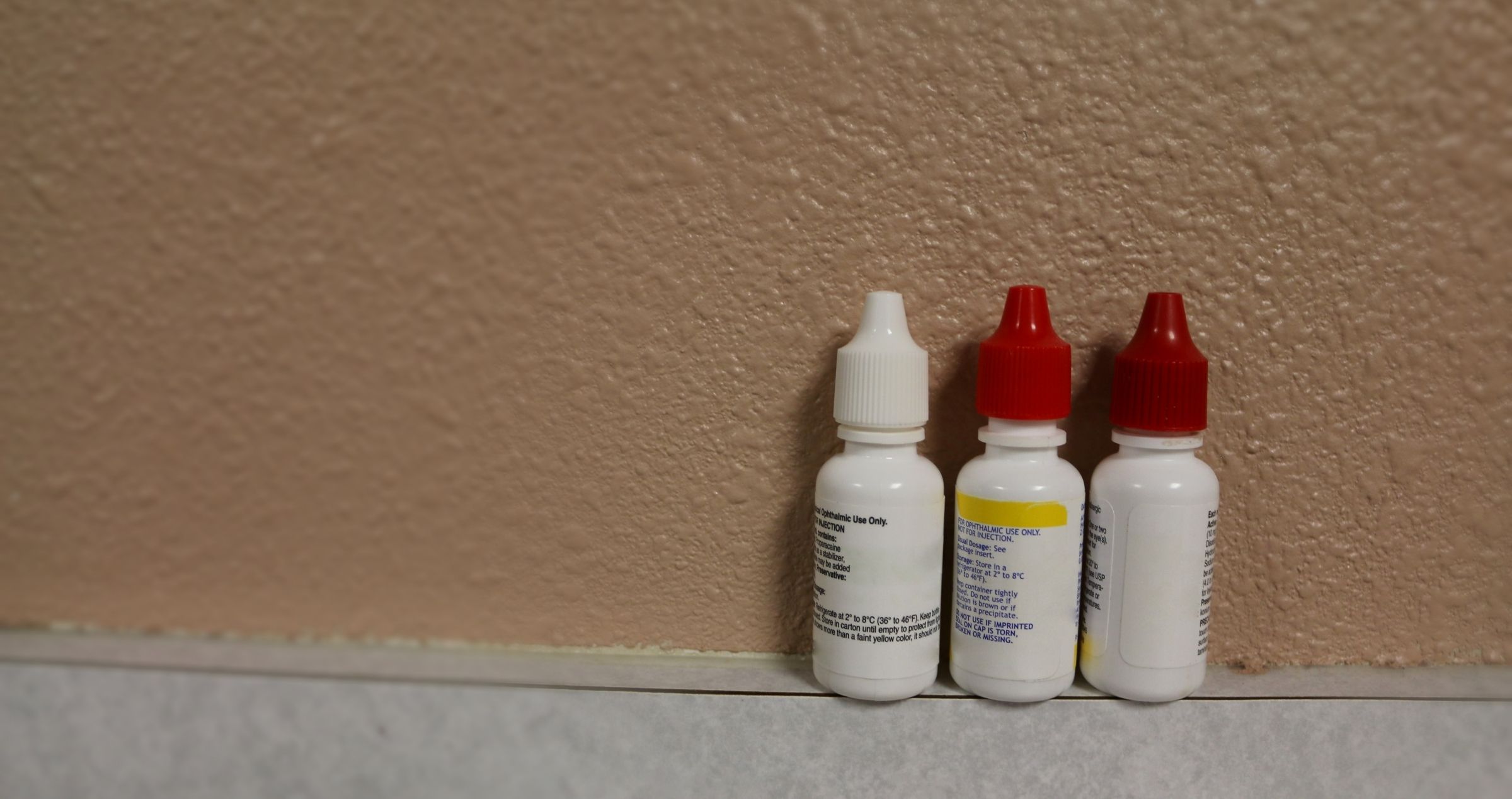 Image of three eye drop bottle placed against a wall