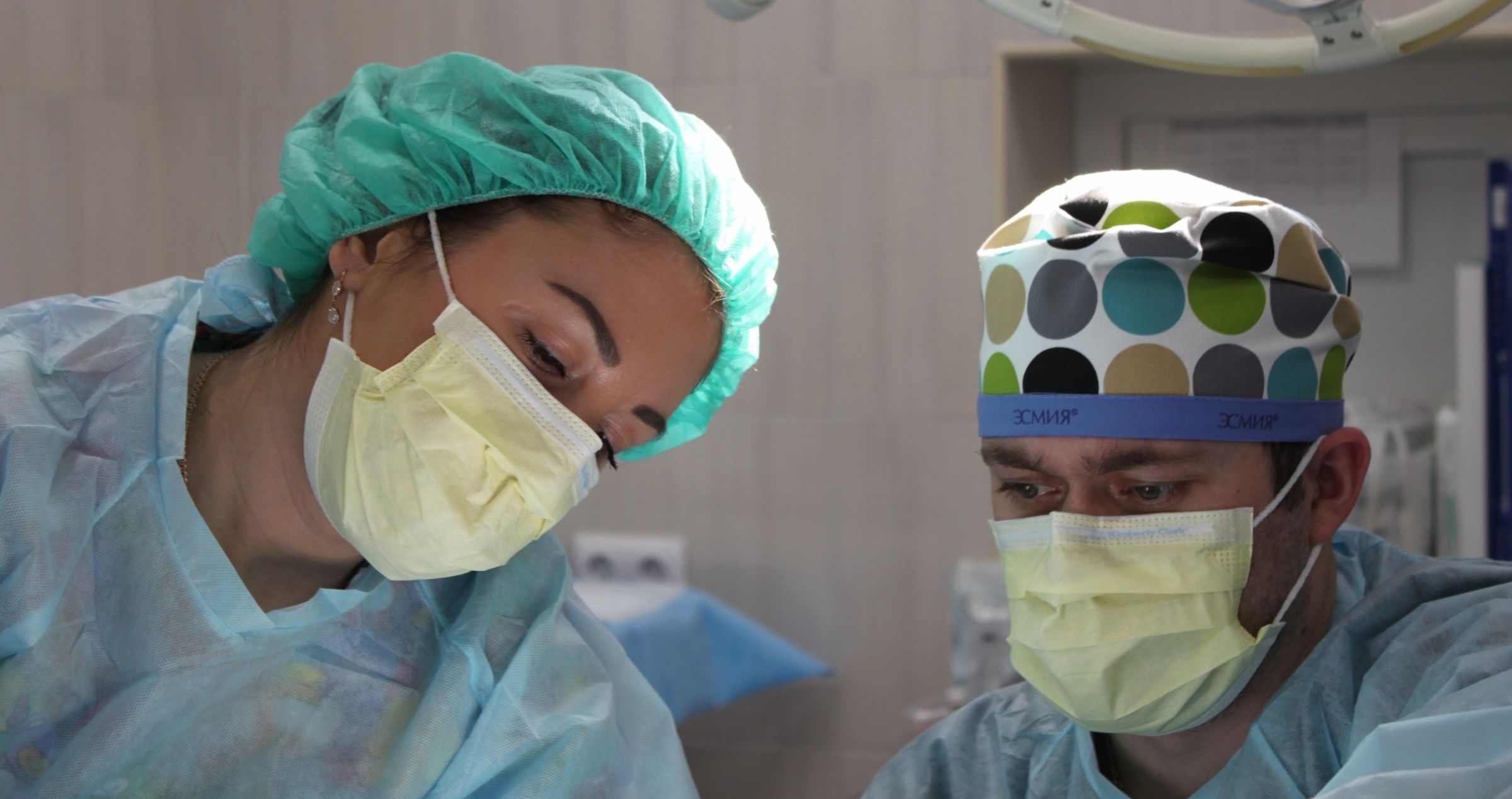 Two surgeons wearing masks and scrubs in operating theatre