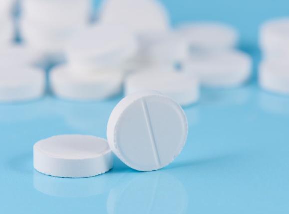 A pile of round white tablets sitting on a light blue surface