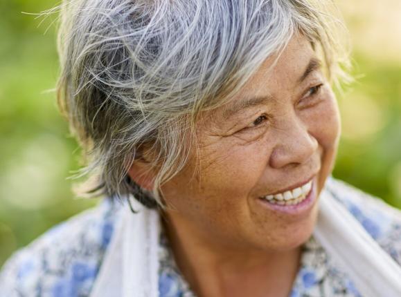 Natural looking Asian woman with wind swept hair smiling and looking to her left