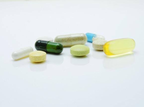Different coloured pills and tablets sitting on a white background