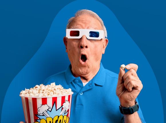 Surprised older gentleman holding popcorn wearing 3D glasses
