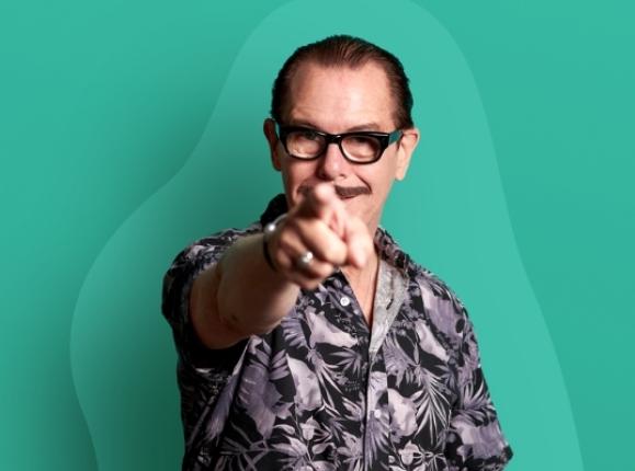 Image of Kirk Pengilly pointing directly at camera with green background