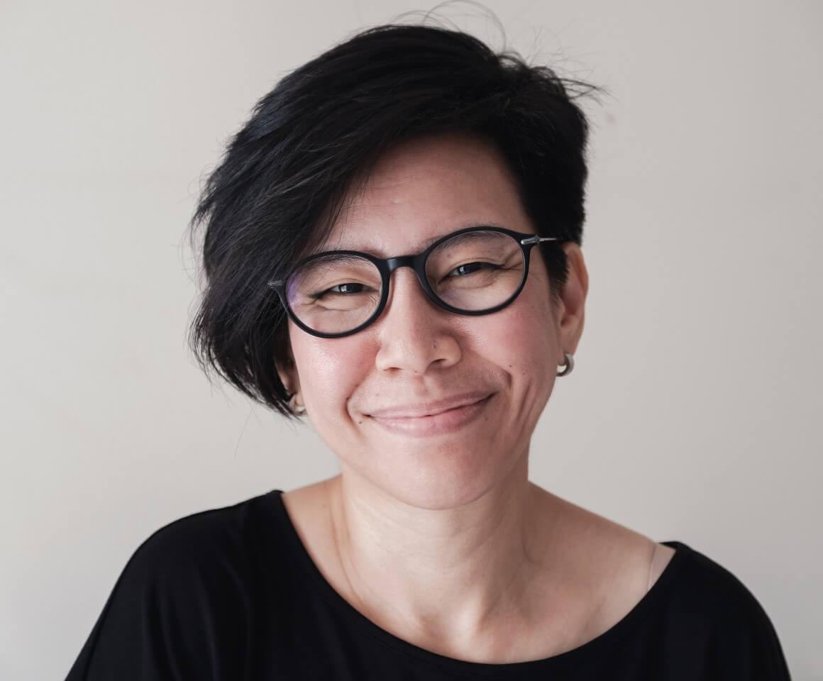 Portrait of happy, natural looking middle aged Asian woman wearing glasses and smiling at camera