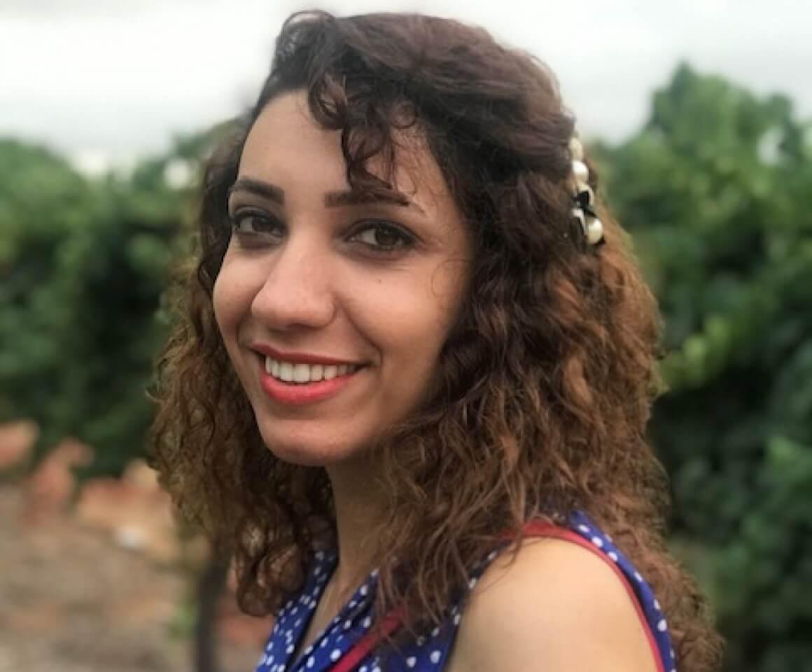 Shabnam standing in a vineyard smiling at the camera