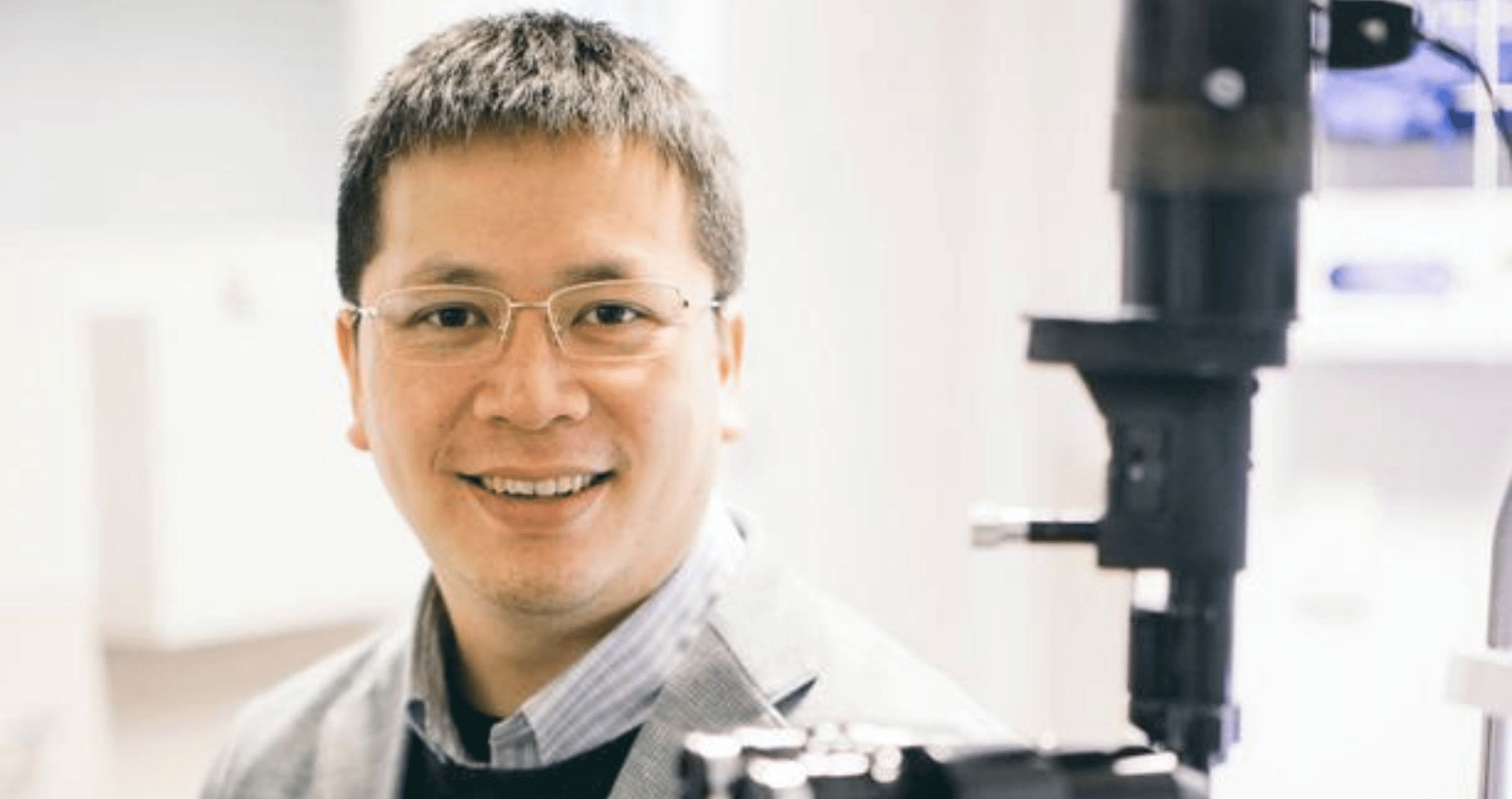 Ophthalmologist, George Kong, seated at microscope